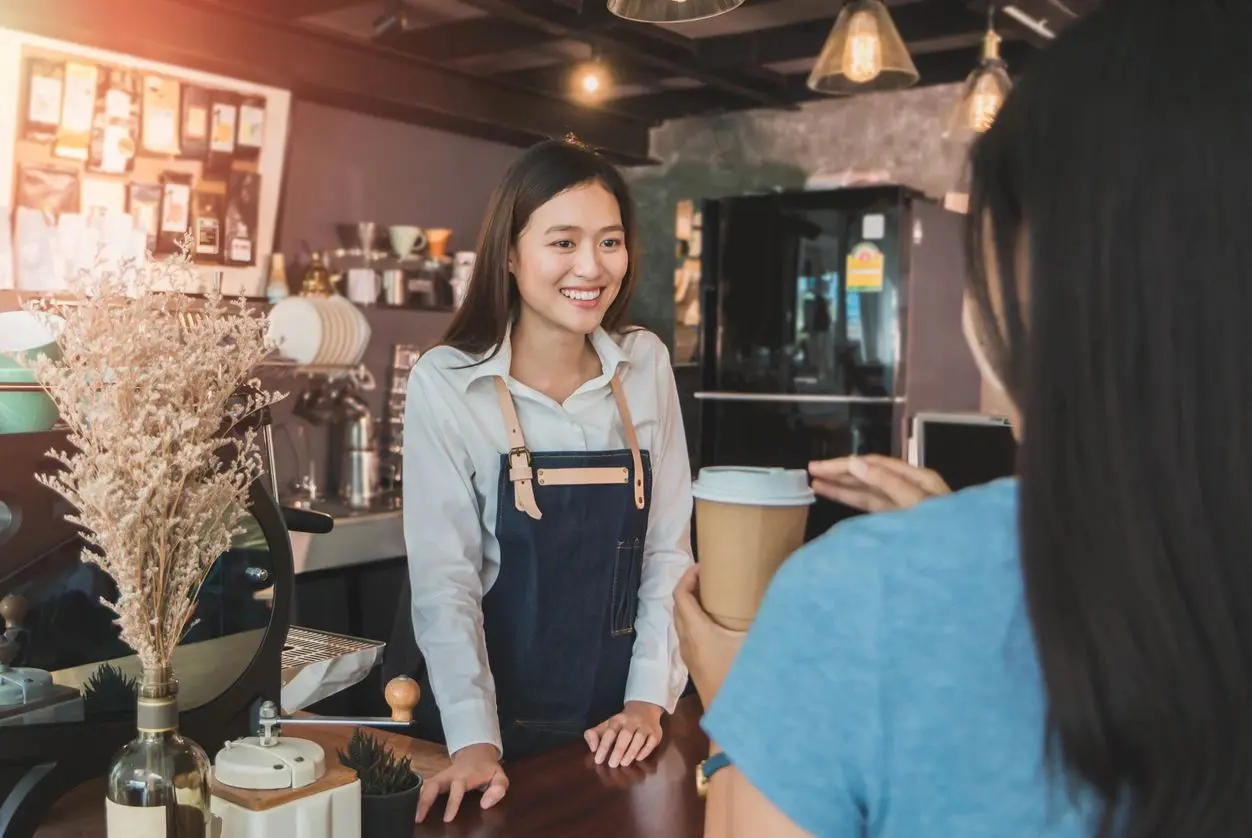 A woman standing at the counter of a coffee shop.